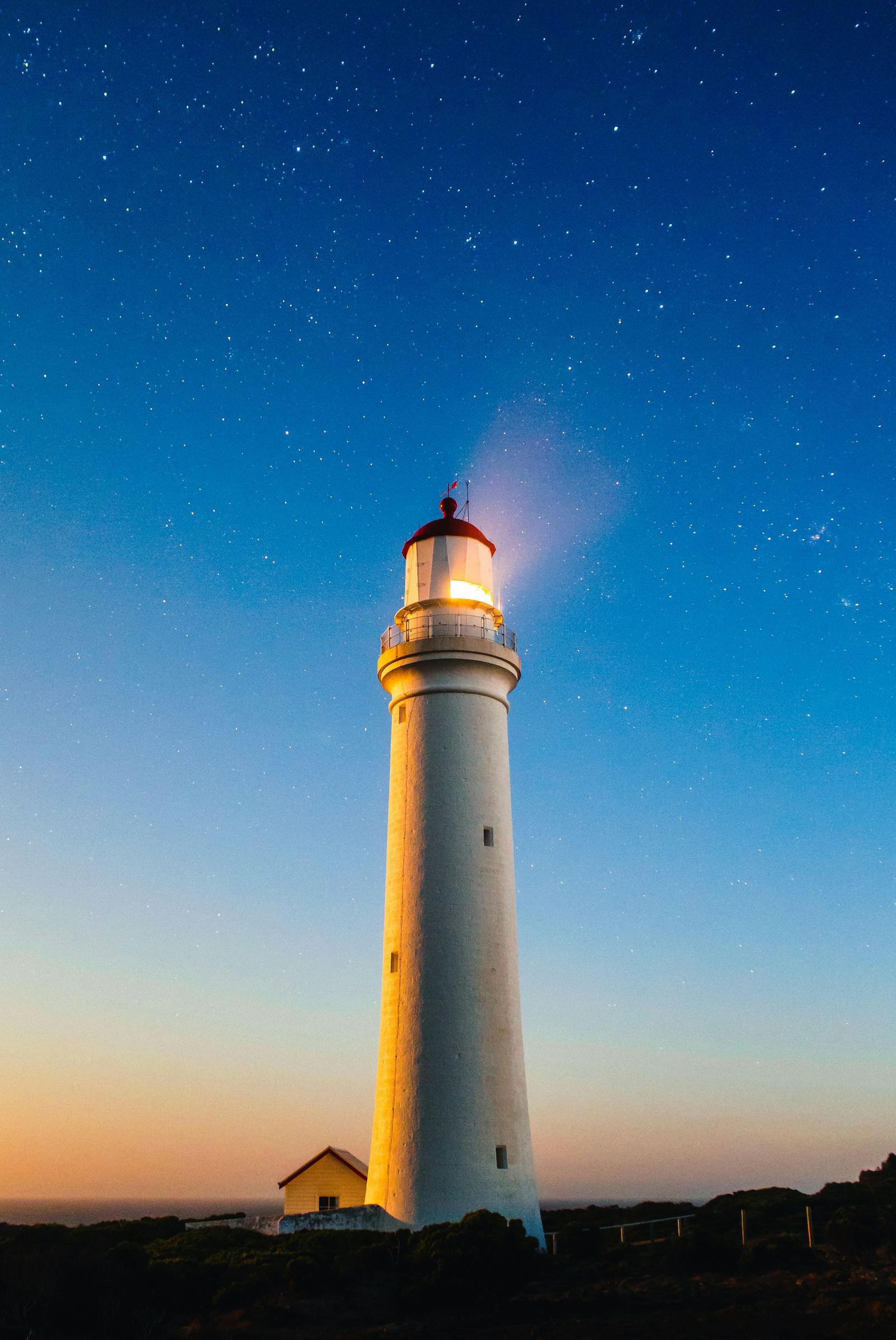 A white lighthouse standing against the sky at night